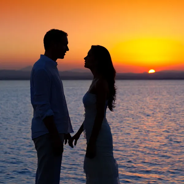 Paar in liefde terug lichte silhouet bij lake zonsondergang — Stockfoto