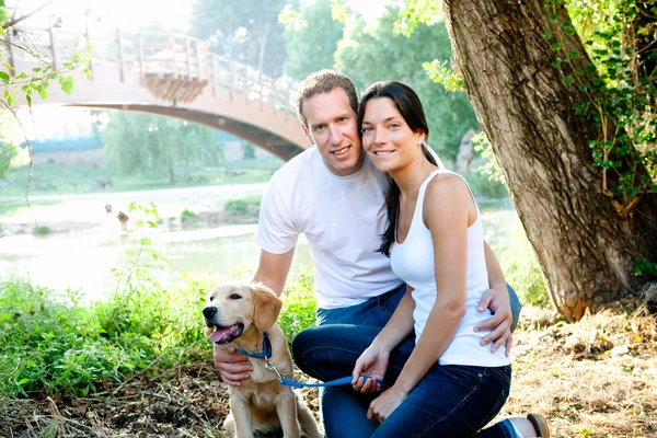 Beautiful couple with puppy in the river — Stock Photo, Image