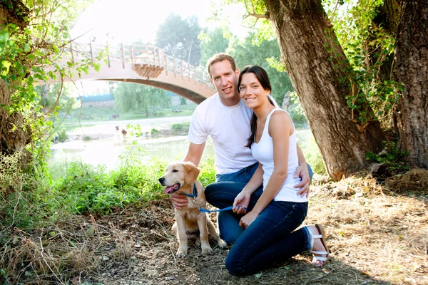 Beautiful couple with puppy in the river — Stock Photo, Image