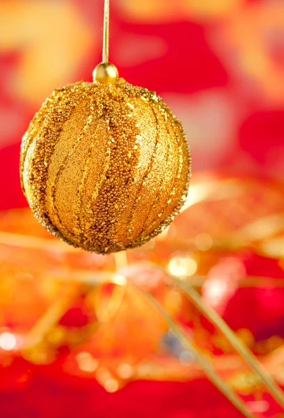 Biglietto natalizio di bauble dorato e sfocatura rossa — Foto Stock