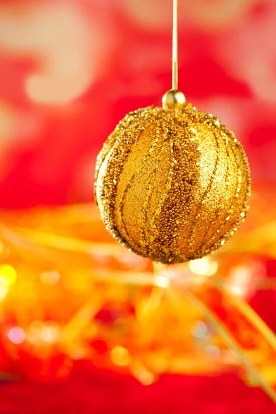 Cartão de Natal de bugiganga dourada e borrão vermelho — Fotografia de Stock