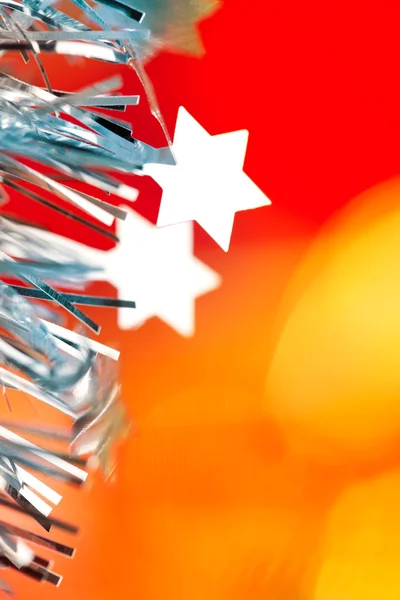 Christmas tinsel stars silver blue on red — Stock Photo, Image