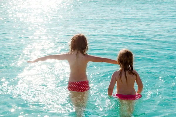 Дети девочки задний вид на пляж на закате — стоковое фото