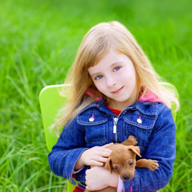 sarışın çocuk kızla yeşil çim içinde evde beslenen hayvan köpek yavrusu