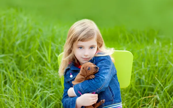Blonďatý kluk holka s štěně psa v zelené trávě — Stock fotografie