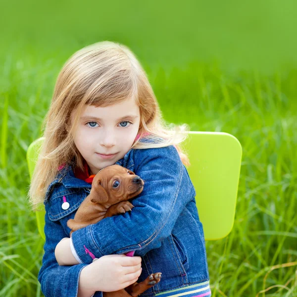 Blonďatý kluk holka s štěně psa v zelené trávě — Stock fotografie