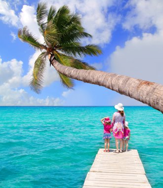 Daughters and mother in jetty on tropical beach clipart