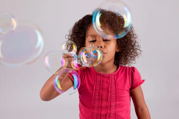 Poco africano asiático chica soplando jabón burbujas —  Fotos de Stock