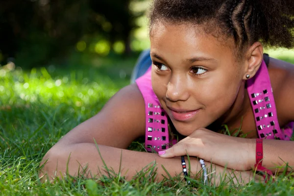 Молодая черная девочка-подросток лежит на траве — стоковое фото