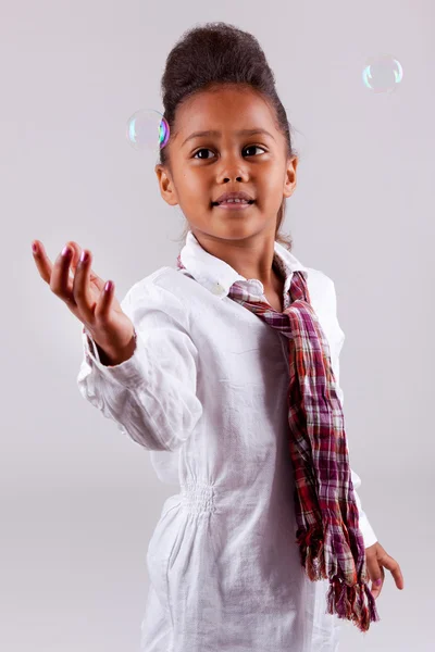 Kleines afrikanisches asiatisches Mädchen bläst Seifenblasen — Stockfoto