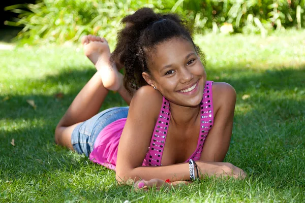 Mladá černá dospívající dívka leží na trávě — Stock fotografie