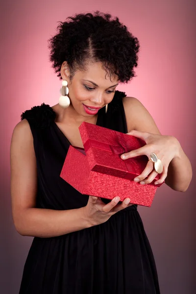 Jovem afro-americana abrindo um presente — Fotografia de Stock