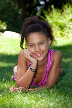 Young black teenage girl lying on the grass clipart