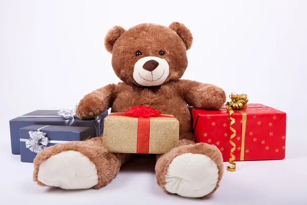 Seated teddy bear with gift boxes — Stock Photo, Image