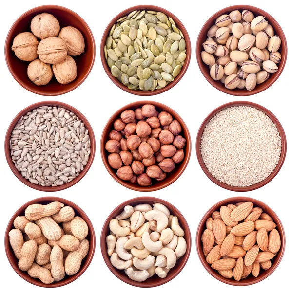 Assortment of nuts and seeds in ceramic bowls isolated on white — Stock Photo, Image