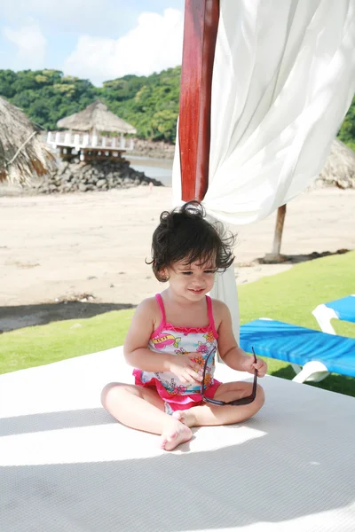 Bebê menina em óculos de sol na praia jogando ficando preparado para — Fotografia de Stock