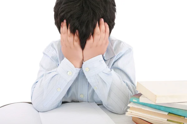 Schooljongen wordt benadrukt door zijn huiswerk, geïsoleerd op witte achterzijde — Stockfoto
