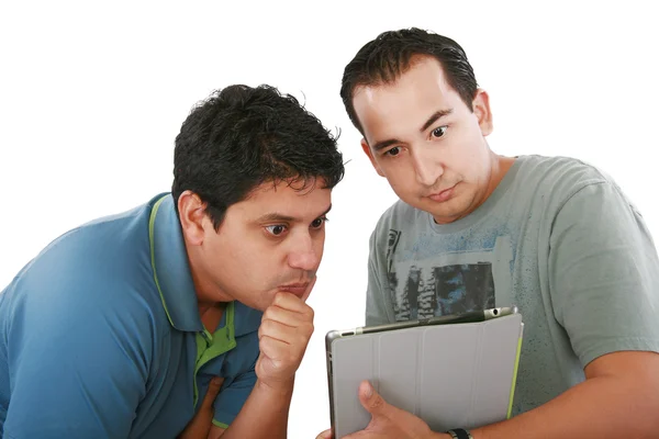 Dois amigos olhando surpreso no computador tablet contra um branco — Fotografia de Stock