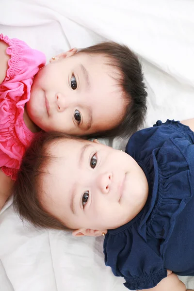 Twin baby sisters lay down in the bed — Stock Photo, Image