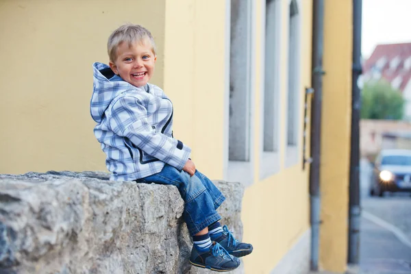 Kleine jongen zit in de buurt van het oude huis — Stockfoto