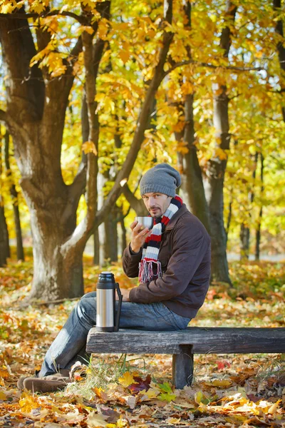 Άνθρωπος πίνει τσάι στο πάρκο φθινόπωρο — Φωτογραφία Αρχείου