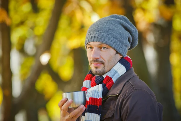 Man drinks tea in autumn park — Stock Photo, Image