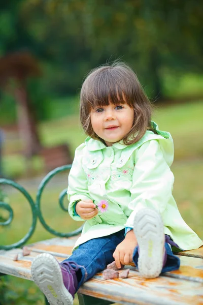 Μικρό κορίτσι κάθεται σε ένα παγκάκι στο πάρκο — Φωτογραφία Αρχείου