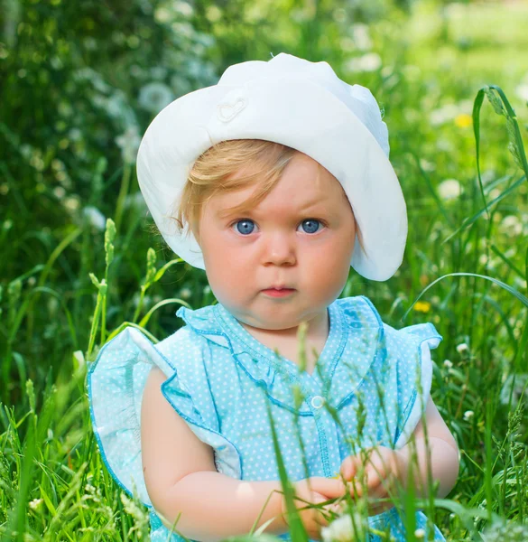 Little girl sitting in the grass in the park — Stock Photo, Image