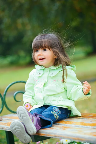 Mała dziewczynka siedzi na ławce w parku — Zdjęcie stockowe
