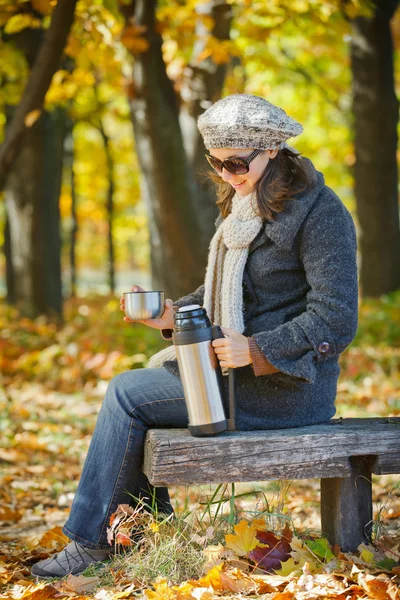 Donna beve tè nel parco autunnale — Foto Stock