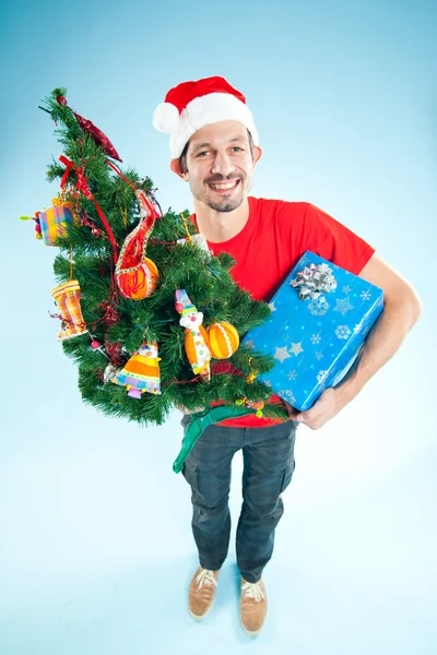 Ένας νεαρός άνδρας με ένα καπέλο santa με χριστουγεννιάτικο δώρο — Φωτογραφία Αρχείου