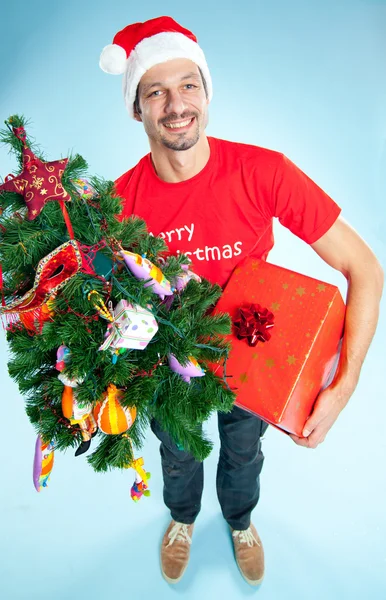 Ein junger Mann mit Weihnachtsmütze und Weihnachtsgeschenk — Stockfoto