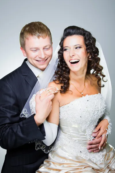 Lachen van bruid en bruidegom op grijs — Stockfoto