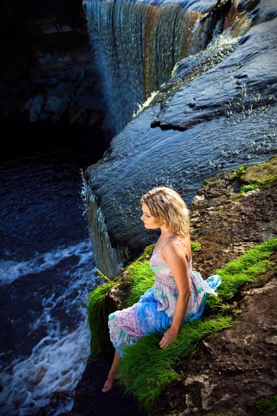 Beautiful girl on brink of precipice of river waterfalls