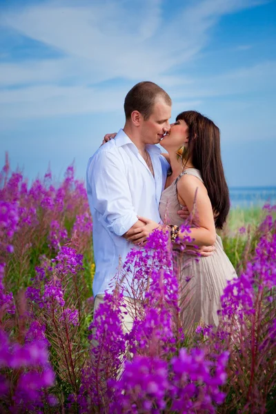 Romantisk kyss bland lila blommor — Stockfoto