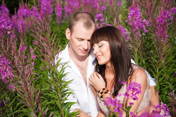Romantic couple among purple flowers — Stock Photo, Image
