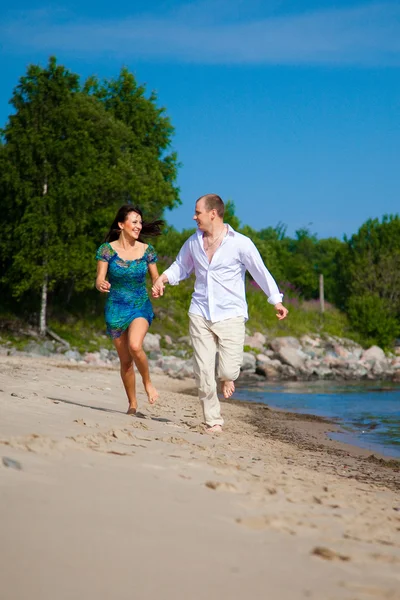 Enamored couple running along the coast of sea — Stock Photo, Image