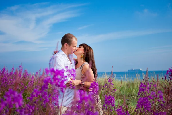 Mavi deniz kenarında mor çiçekler arasında romantik öpücük — Stok fotoğraf