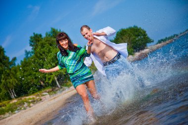 Enamored couple running along the coast of sea clipart