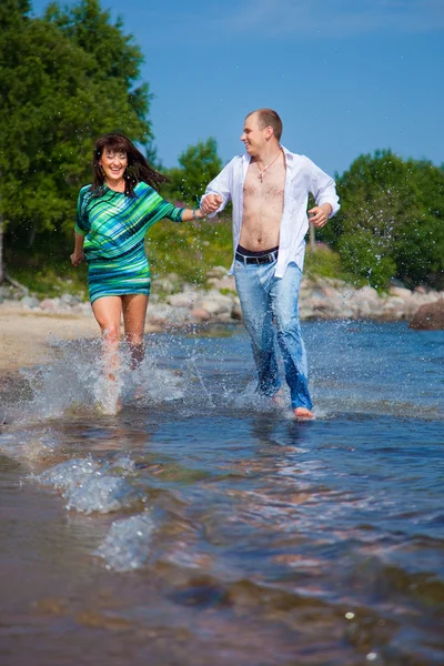 Zakochana para biegnie wzdłuż wybrzeża Morza — Zdjęcie stockowe