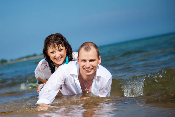 Enamorado homem e menina deitado em ondas de praia de areia — Fotografia de Stock