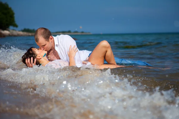 Enamorado homem e menina beijando em ondas de praia de areia — Fotografia de Stock