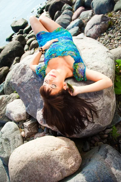 Mooie brunette meisje liggend op het strand stenen — Stockfoto