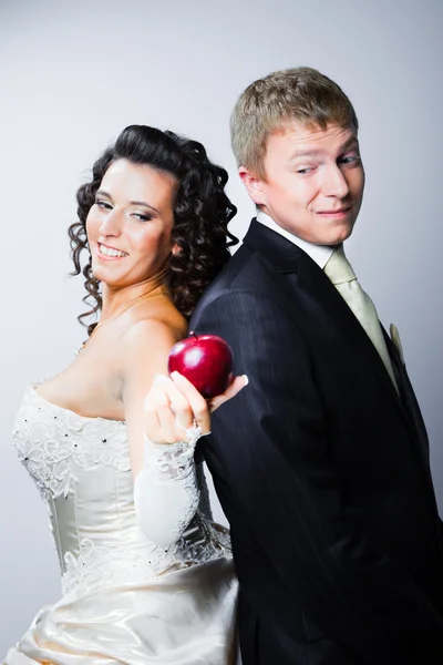 Braut bietet zweifelnden Bräutigam einen roten Apfel an — Stockfoto