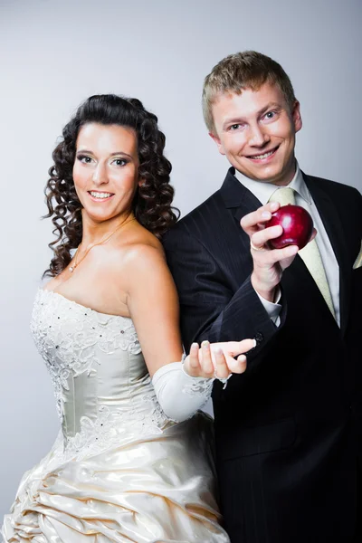 Groom taking red apple from young beautiful bride — Stock Photo, Image