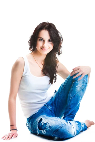 Hübsche Frau in blauen Jeans sitzt auf weißem Boden — Stockfoto