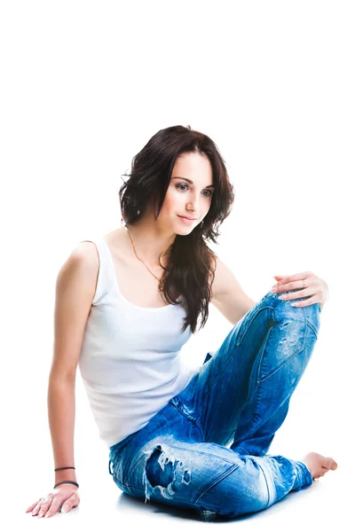 Hezká žena v modré džíny sedí na bílé — Stock fotografie