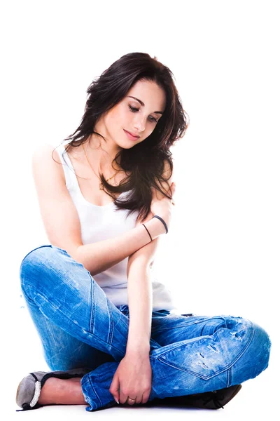Mulher bonita em jeans azul sentado no chão branco — Fotografia de Stock