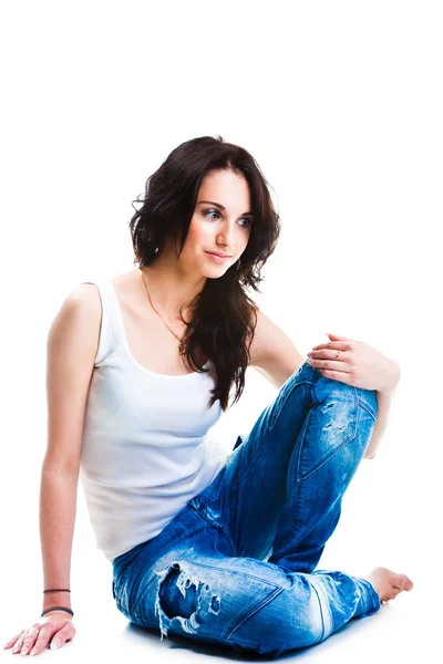 Vacker kvinna i blå jeans sitter på vita golv — Stockfoto