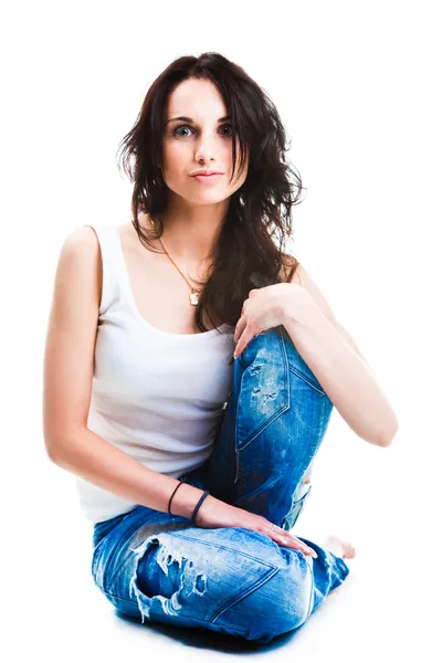 Όμορφη γυναίκα με μπλε τζιν που κάθεται στο λευκό δάπεδο — Φωτογραφία Αρχείου